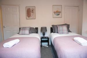 Duas camas sentadas uma ao lado da outra num quarto em Coral Place em Luton