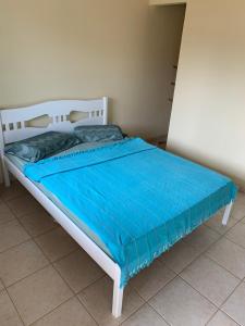 a bed with a blue blanket on top of it at Suítes Maresias in São Sebastião