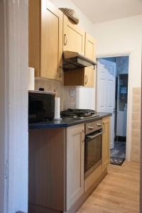 uma cozinha com armários de madeira e um forno com placa de fogão em Coral Place em Luton