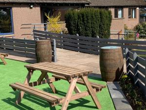 a wooden picnic table and two barrels on the grass at Lunan House in Arbroath