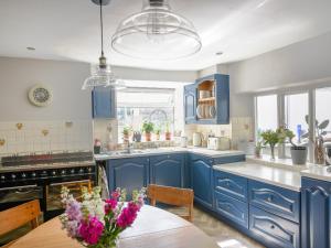 a kitchen with blue cabinets and a table with flowers on it at The Fernery in Colyton