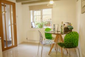 南維爾的住宿－Southwell Holiday Cottage - Lavender Cottage，一间带桌子和绿色椅子的用餐室