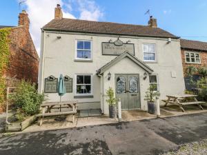 a building with two picnic tables in front of it at Pheasant in Carthorpe +14 photos
