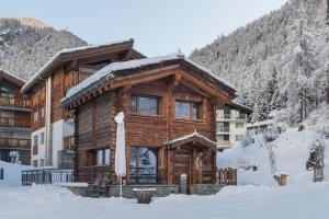 una cabaña de madera en la nieve frente a un edificio en Piccola Fiamma by Pizzo Fiamma en Zermatt
