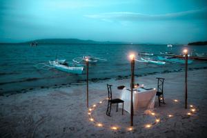 a table and chairs on the beach with lights at Blue Moon Inn in Dauis