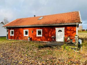 a red house with a white door in a field at Ruth & Iris Cottage in Nässjö