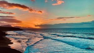a sunset over the ocean with waves at Wellenkind Surfschool in La Pared
