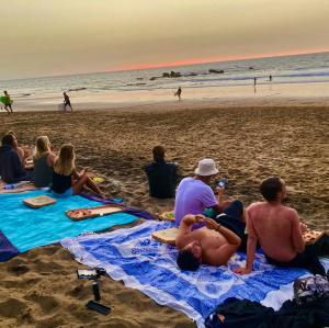 a group of people sitting on a blanket on the beach at Wellenkind Surfschool in La Pared