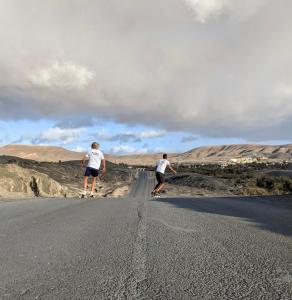 two men walking down a road in the desert at Wellenkind Surfschool in La Pared
