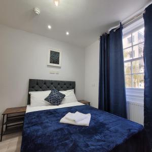 sypialnia z łóżkiem z niebieskim kocem i oknem w obiekcie Argyle Square Hotel w Londynie