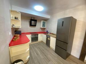 eine Küche mit einer roten Theke und einem Kühlschrank in der Unterkunft Casa en Montealegre reformada y acogedora (wifi) in Sámano