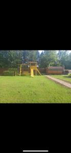 a playground with a yellow slide in the grass at Sodo namelis 