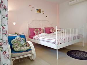 a childs bedroom with a white bed and a chair at Better Weather Homestay in Pak Chong