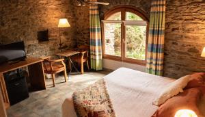 a bedroom with a bed and a table and a window at Mas D'en Roqueta in Aravell