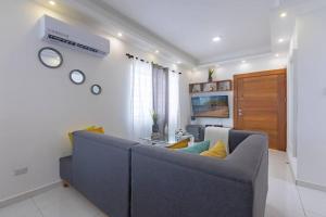 ein Wohnzimmer mit einem blauen Sofa und einem TV in der Unterkunft Villa Escondida #3 In the center of POP city in San Felipe de Puerto Plata