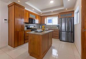 a kitchen with wooden cabinets and a stainless steel refrigerator at Villa Escondida #3 In the center of POP city in San Felipe de Puerto Plata