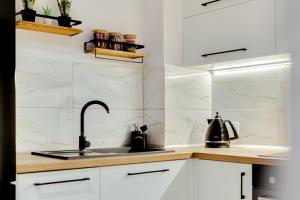 a kitchen with white marble walls and a sink at Apartament na parterze 40 m od rynku in Gliwice