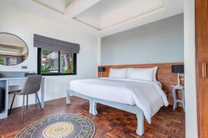 Schlafzimmer mit einem weißen Bett und einem Schreibtisch in der Unterkunft Vikasa Yoga Retreat in Koh Samui 