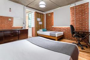 a bedroom with a bed and a desk and a brick wall at Ayenda Casa Miranda Airport in Mexico City