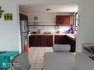 uma cozinha com armários de madeira e uma mesa e cadeiras em Conjunto vacacional Cocomar-Casa 6-4h em Carrizal