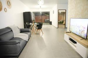 uma sala de estar com um sofá e uma televisão de ecrã plano em Lodge Palmeraie & son Jacuzzi exclusif em Matoury