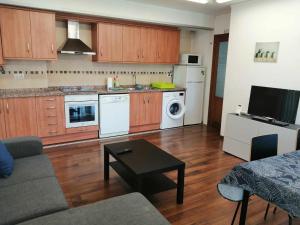 a living room with a couch and a kitchen with white appliances at Apartamento Ibañez Martín in Mora de Rubielos
