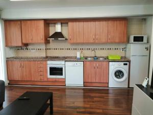 a kitchen with wooden cabinets and a washer and dryer at Apartamento Ibañez Martín in Mora de Rubielos