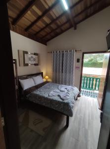 sypialnia z łóżkiem i dużym oknem w obiekcie CHALES CARVALHOS w mieście Monte Verde