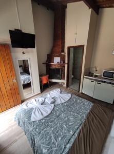 sypialnia z łóżkiem oraz kuchnia z kominkiem w obiekcie CHALES CARVALHOS w mieście Monte Verde