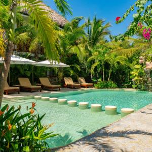 uma piscina num resort com cadeiras e palmeiras em Muúnek Hotel Boutique Art & Spa em Barra Vieja