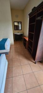 a room with a bed and a cabinet and a tiled floor at Hotel Real del Rio in Rio Dulce
