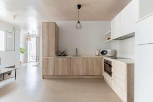a kitchen with white walls and wooden cabinets at Erizo 3 loft diafáno en el Centro Histórico in Tarifa +20 photos