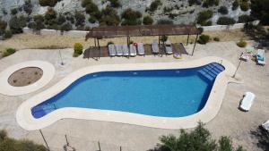 een uitzicht op een zwembad met stoelen en een parasol bij Casas Rurales Cortijo Leontino in Taberno