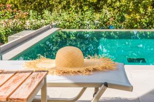 コントカリにあるMy Mediterranean Corfu Luxury Villa with Private Swimming Poolのプール横のベンチに座るわら帽子