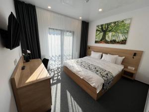 um quarto com uma cama, uma secretária e uma televisão em HELIOS Boutique Hotel em Săcele