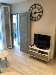 a living room with a tv and a clock on the wall at Vieil Antibes, ravissant 2p avec petite terrasse in Antibes