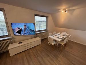 a living room with a table and a flat screen tv at Schöne Wohnung an der Nordsee in Mildstedt in Mildstedt