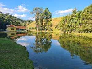 uma vista para um lago com uma casa e árvores em Chalés Tia Nastácia em Monteiro Lobato