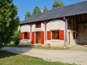 Une vieille maison avec des volets rouges dans l'établissement Gîte de l'orangerie du château de Jallanges- 11 personnes, à Vernou-sur-Brenne