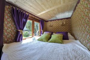 1 dormitorio con 1 cama grande y cortinas moradas en Roulotte Insolite avec terrasse proche Paris en Noisy-le-Grand