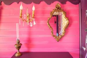 大諾瓦西的住宿－Roulotte Insolite avec terrasse proche Paris，粉红色的墙,墙上有镜子,桌子上还有蜡烛