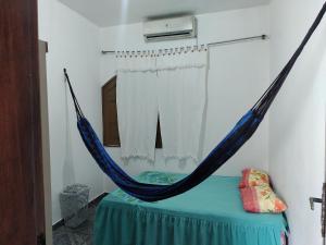 uma cama com rede de descanso num quarto em Casa grande em área central, bem iluminada e vent. em Manaus