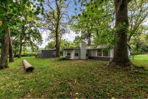 a house in the middle of a yard with trees at Cozy Lakefront Cottage Getaway Branson MO. in Branson