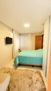 Schlafzimmer mit einem Bett, einem TV und einem Teppich in der Unterkunft DELUX BEIRA-MAR NATAL Flat in Natal