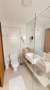 La salle de bains blanche est pourvue de toilettes et d'un lavabo. dans l'établissement DELUX BEIRA-MAR NATAL Flat, à Natal