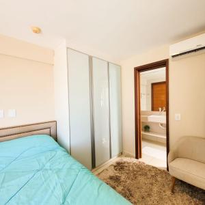 a bedroom with a bed and a chair and a mirror at DELUX BEIRA-MAR NATAL Flat in Natal