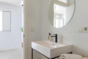 Baño blanco con lavabo y espejo en Erizo 3 loft diafáno en el Centro Histórico, en Tarifa