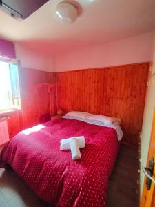 a bedroom with a red bed with two towels on it at Faggio Rosso in Filettino