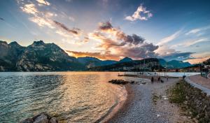 a group of people walking on a beach next to a body of water at Torbole Aparthotel in Nago-Torbole