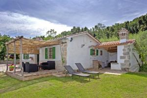 a white house with a table and chairs in a yard at Roinizza in Prtlog (Haus für 4-5 Personen) in Labin